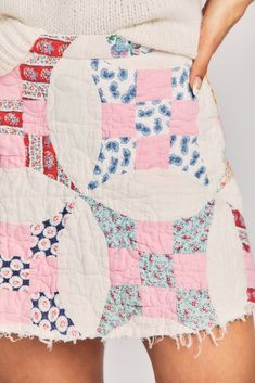 a woman wearing a skirt made out of patchwork fabric and pink, white and blue material