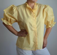 Vintage bright yellow folk women's blouse with short puff sleeves with cutout lace, which is also used on the hems of the collar. Free falling shape of the body Era -  1980s era Material  - missing tag, cotton/ polyester blend  Size - marked 44 DE *, shown on 40 DE, cup size D, obviously fits big. *This is the vintage size, please look at measurements below to see if it will fit you: Approximate Measurements (taken when blouse lying flat, double armpit to armpit): Shoulder to Shoulder (from seam Spring Cottagecore Puff Sleeve Top, Fitted Cotton Shirt With Puff Sleeves, Cotton Fitted Shirt With Puff Sleeves, Yellow Puff Sleeve Top With Ruffles, Feminine Yellow Blouse For Daywear, Yellow Feminine Blouse For Daywear, Yellow Fitted Shirt For Fall, Fitted Yellow Shirt For Fall, Yellow Feminine Blouse