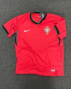 a red soccer jersey on the ground with black and green trims, worn by portugal's national team