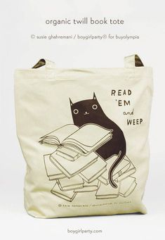 an organic tote bag with a black cat reading a book on top of it