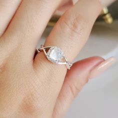 a woman's hand with a diamond ring on her finger and an oval shaped white pearl in the middle