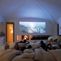 two people laying on bean bag chairs in front of a large screen with a fireplace