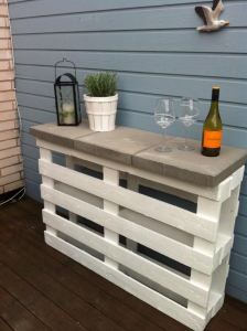 a table made out of pallets with wine glasses on it and a bottle of wine