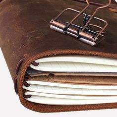 an open brown leather book with three binders on the front and one in the middle