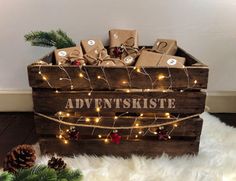 a wooden crate filled with christmas presents on top of a white fluffy rug next to pine cones