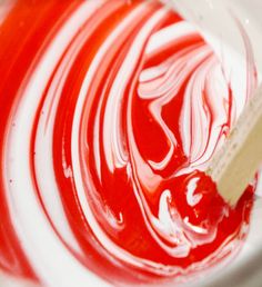 a red and white swirled liquid with a wooden stick sticking out of the top in a bowl