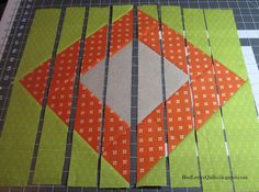 an orange and green patchwork design on a piece of fabric that has been cut into squares