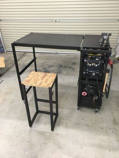 a workbench with a table and stool in front of it, next to a garage door