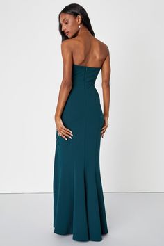 a woman in a strapless dress is looking back at the camera and she has her hands on her hips