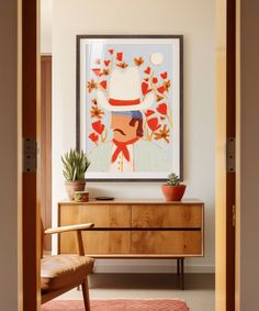 a painting hangs on the wall next to a wooden dresser with a plant in it