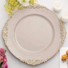 a white plate with gold trim and flowers on it, next to two tea lights