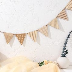 there is a white vase with flowers on the table next to a tan and brown bunting banner