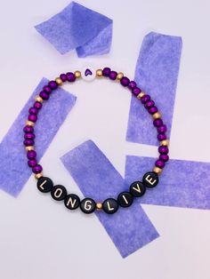 a beaded necklace with the word long live spelled in black letters on purple paper