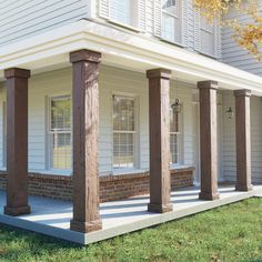 the front porch of a white house with columns and windows on each side is covered in wood