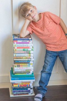 a young boy leaning against a stack of books