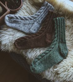 three pairs of socks sitting on top of a furry rug next to a potted plant