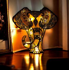 an elephant shaped lamp is lit up on the floor next to a mirror and wall