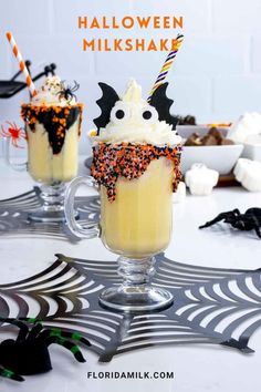 two halloween milkshakes with sprinkles and candy on the rim, sitting on a table