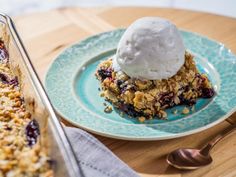 a blue plate topped with a piece of cake next to a serving dish filled with ice cream