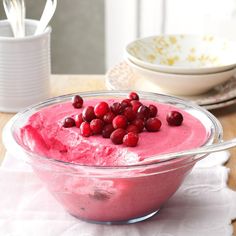 a bowl filled with cranberry sauce on top of a table next to plates and utensils