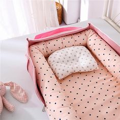 a pink baby bed with polka dots on it and a pillow in the middle that has been placed inside