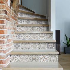 a stair case with decorative tiles on the riser and handrails next to a brick wall