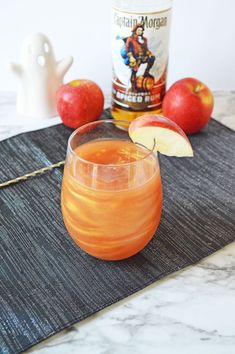 an apple cider sitting on top of a table next to some apples