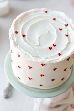 a cake with white frosting and red hearts on it