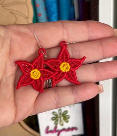 a hand holding a pair of red and yellow star earrings