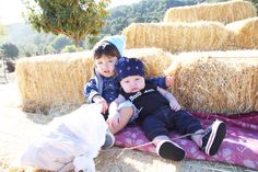 two children sitting on a blanket in front of hay bales