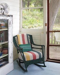 a rocking chair sitting in front of a window next to a book shelf filled with books