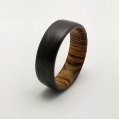 a wooden ring is shown on a white surface with black wood inlaying it