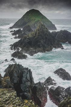 an island in the middle of the ocean with waves crashing on it's rocks