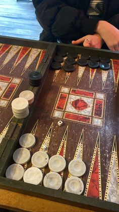 a close up of a person playing a game of backgamh on a table