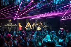 a group of people that are standing in front of a stage with some lights on