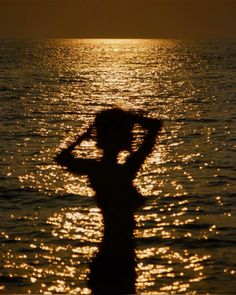 a person standing in the water with their hands on their head and arms behind their backs