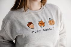 Get ready for fall in our cute 'cozy season' pullover sweatshirt. Cute Cozy Fit Tops For Fall, Cute Fall Sweater With Ribbed Cuffs, Cozy Embroidered Sweatshirt For Winter, Cute Sweater With Ribbed Cuffs For Fall, Cute Fall Loungewear Sweatshirt, Cute Embroidered Sweatshirt For Loungewear, Cozy Embroidered Long Sleeve Sweatshirt, Cute Fall T-shirt, Winter Embroidered Graphic Sweatshirt For Loungewear