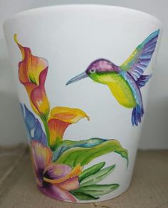 a white cup with a colorful hummingbird painted on it