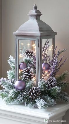 a lantern filled with christmas decorations on top of a white mantle next to a tree