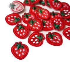 small red crocheted strawberries with green leaves and dots on white table top