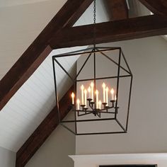 a chandelier hanging from the ceiling in a room with exposed wood beams