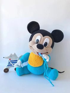 a crocheted mickey mouse sitting next to a small toy dog on a white surface