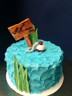 there is a blue cake with green icing on the top and an orange sign above it