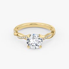 a yellow gold engagement ring with a round cut diamond in the center and pave set shoulders