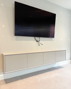 a large flat screen tv mounted to the side of a white wall in a living room