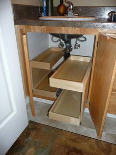 an open cabinet in the corner of a bathroom with sink and faucet above it