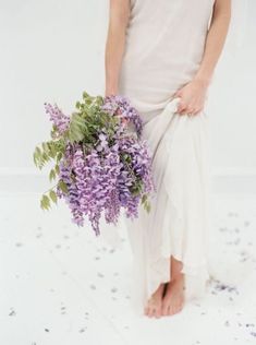 a woman holding a bouquet of purple flowers