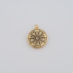 a small gold compass charm on a white background