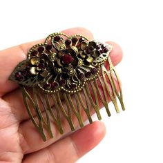 Capturing the elegance of the Victorian Renaissance era this stunning brass filigree deep red bling hair comb with a unique character is perfect for a stylish antique look for any special dress occasion or just to complement your unique style. A gorgeous hair adornment will add a touch of timeless vintage glamour to any outfit. A perfect Christmas or Valentine's romantic gift idea for her. This sophisticated exotic nature-inspired floral hair accessory features antique brass combs accented with hand-formed flower settings and handset dark red glass crystal rhinestones with antique brass delicate leaves on both sides surrounded by matching color multiple tiny crystal rhinestone beads. The comb is just over 2" (5.2 cm) long and 2.1" (5 5 cm) tall. The teeth of the comb measure 3 cm in length Vintage Hair Jewelry, Victorian Era Accessories, Hair Combs, Victorian Hair Pieces, Ornate Red Ceremonial Jewelry, Red Hair Ornaments, Victorian Hair Locket, Hair Lockets Victorian, Vintage Hair Comb