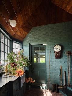 a kitchen with a clock on the wall next to a green door and window sill